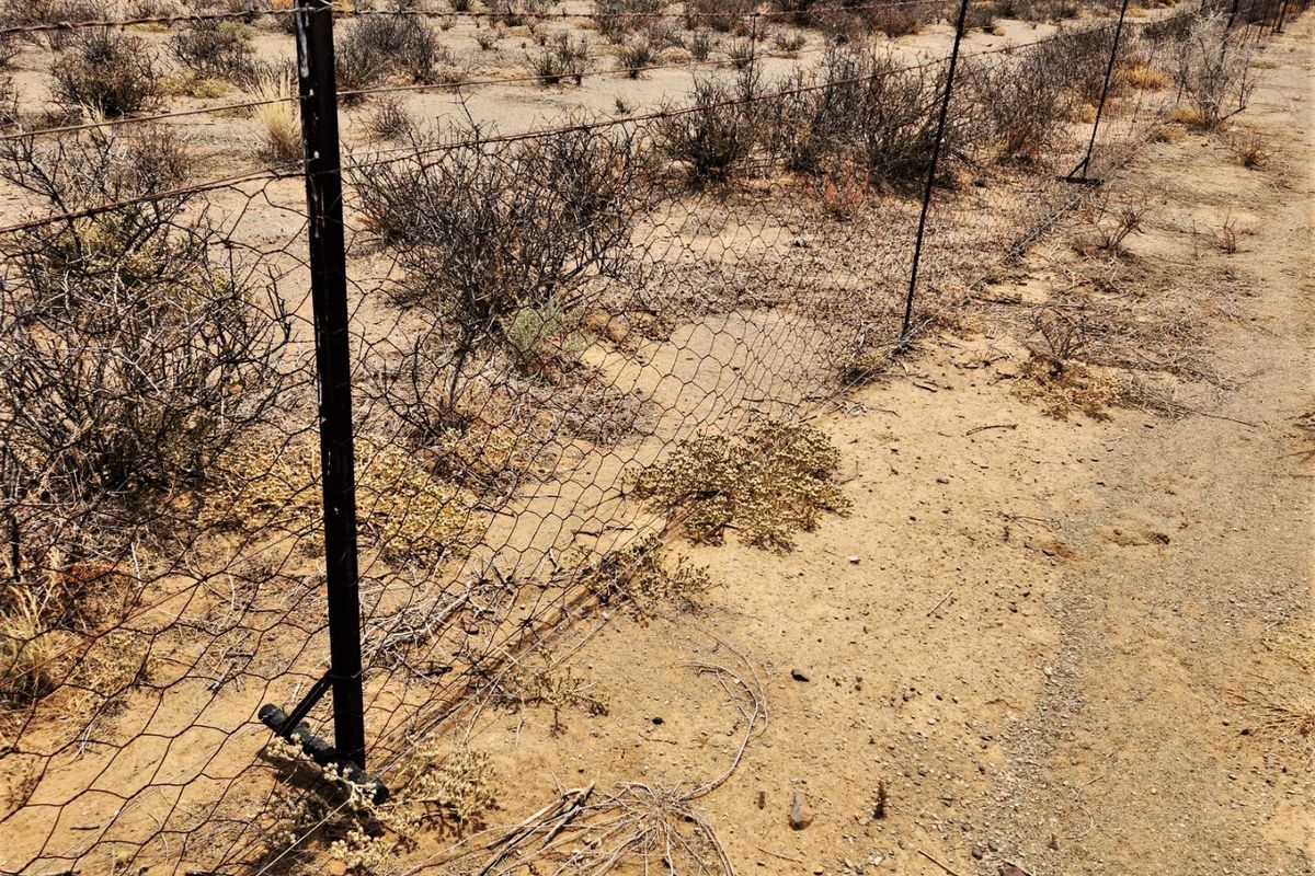 A view of the farm perimeter featuring wire mesh fencing supported by metal posts, showing signs of weathering and wear.