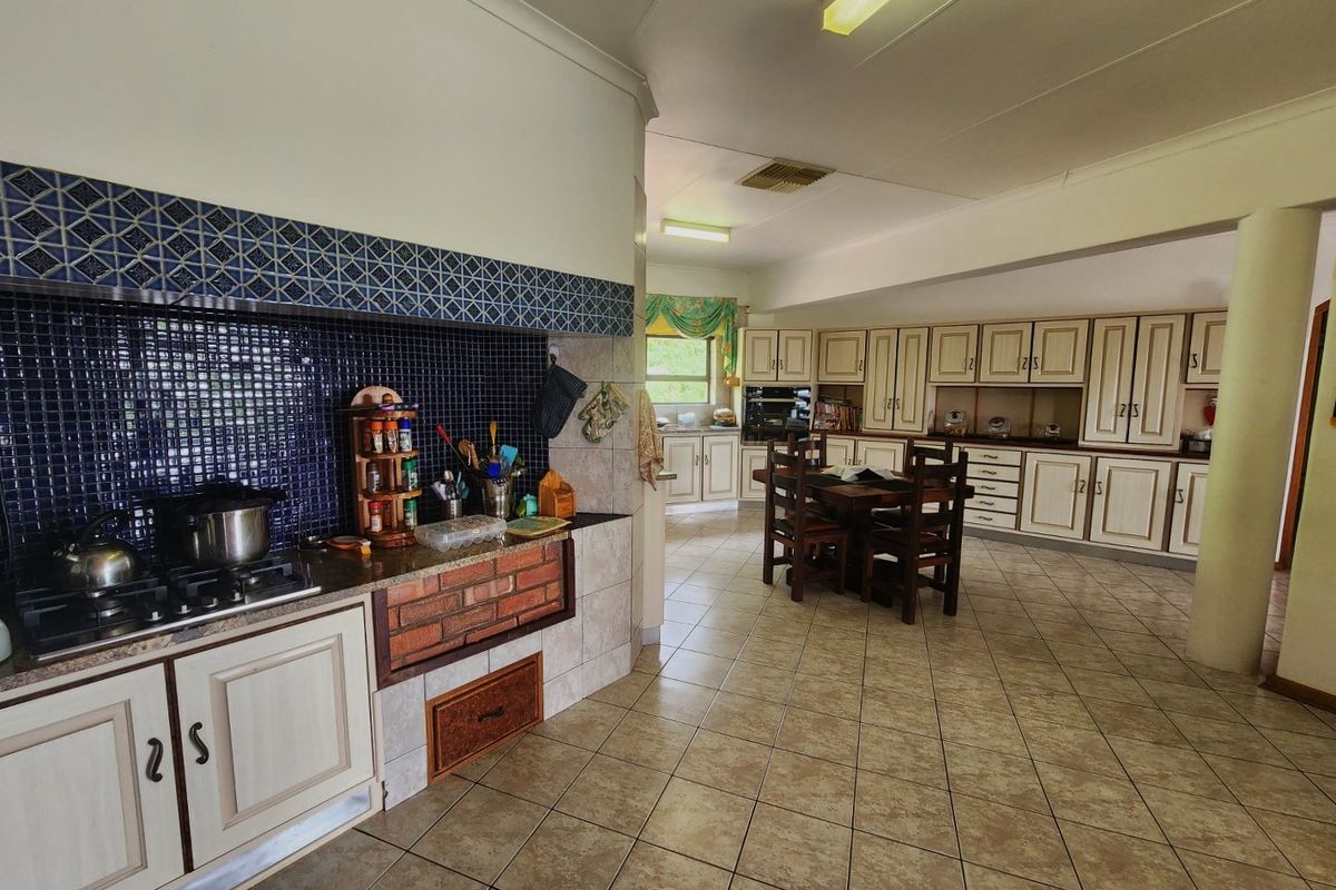 Spacious kitchen featuring extensive built-in cabinetry, a gas hob with tiled splashback, and ceramic floor tiles throughout.