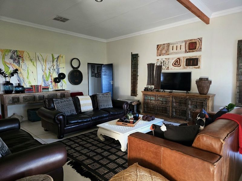 Spacious living room featuring tiled flooring, coved cornicing, and an exposed timber ceiling beam, creating a warm and inviting atmosphere.