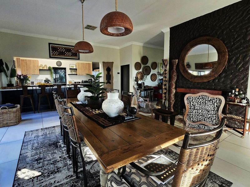 Spacious open-plan living and dining area featuring a striking stone-clad fireplace, modern kitchen cabinetry, and a central island, creating a cohesive and inviting atmosphere.