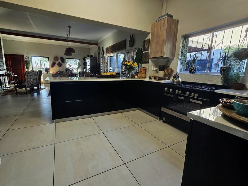 Spacious open-plan kitchen featuring modern black cabinetry, a central island, and a gas stove, seamlessly flowing into the adjacent living and dining area.