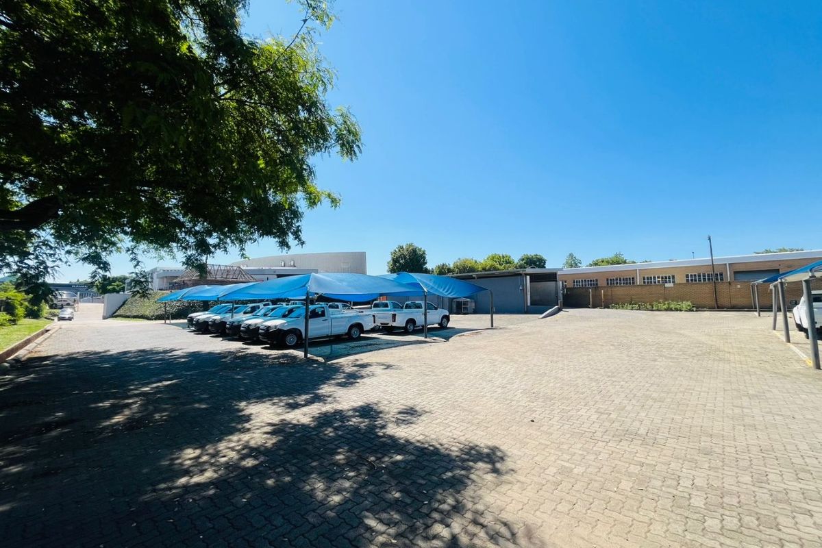 Spacious paved commercial parking area featuring multiple shade cloth carports and access to the rear of the industrial building.