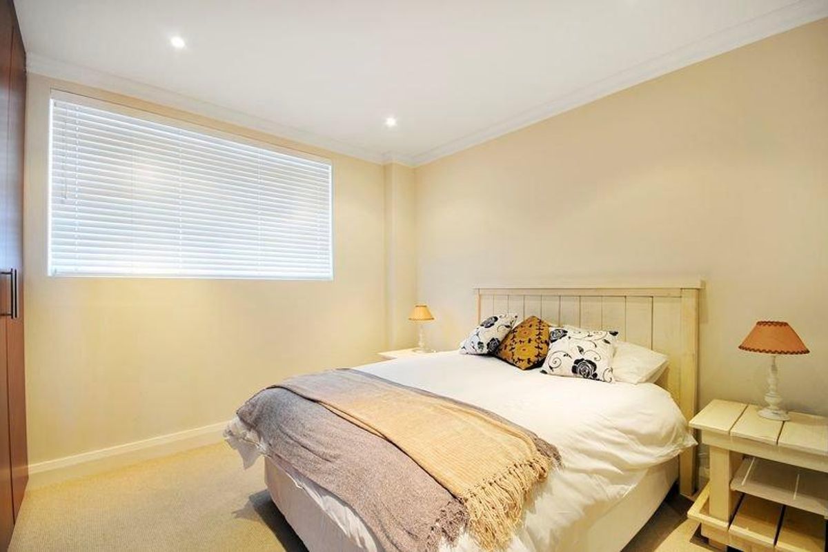A well-maintained bedroom featuring neutral walls, recessed downlighting, built-in cabinetry, and venetian blinds.
