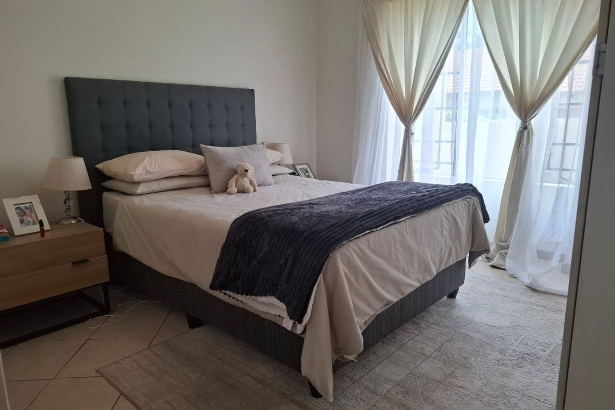 A well-lit bedroom featuring tiled flooring and large windows with curtain treatments, providing a comfortable and functional living space.