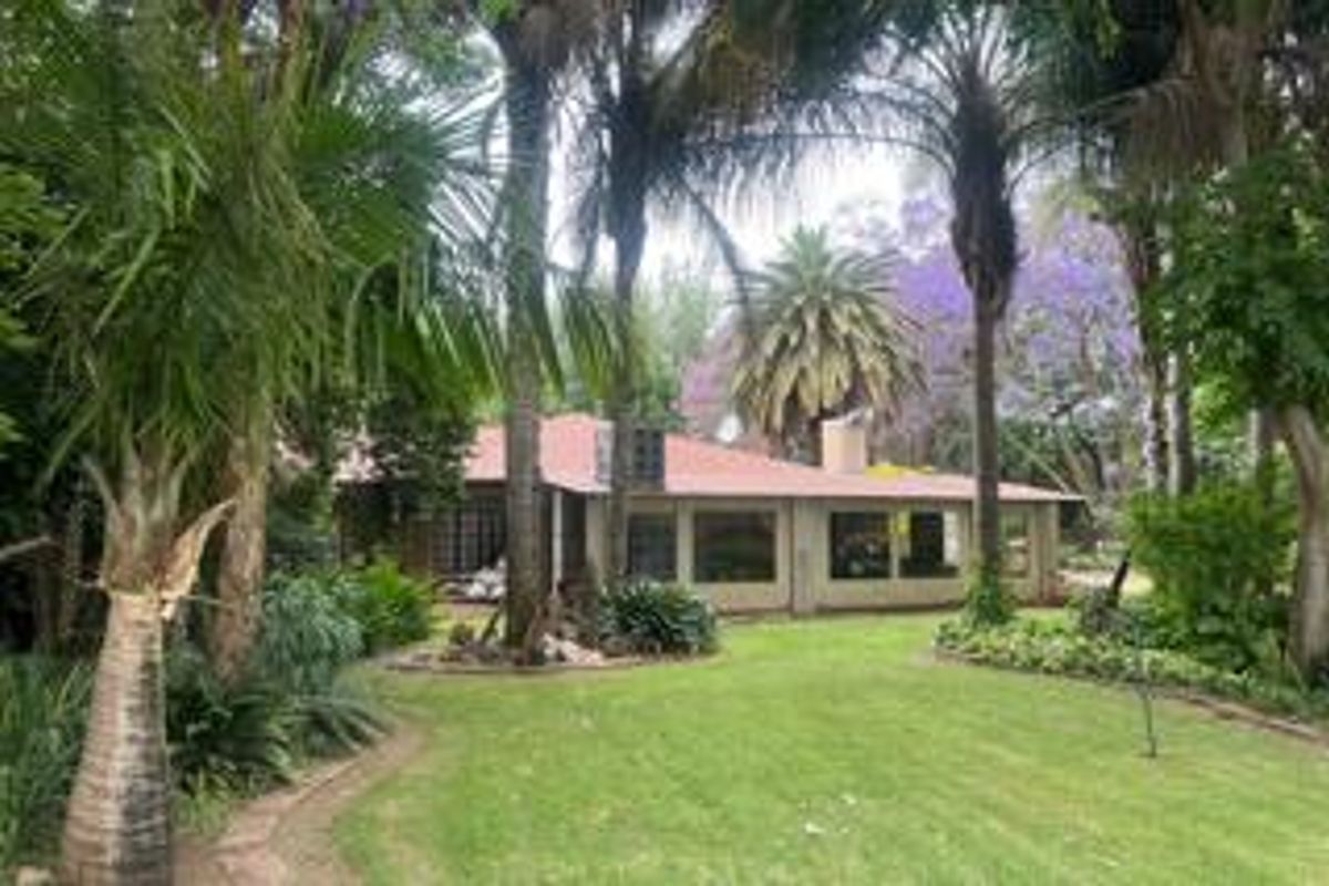 A view of the rear elevation of the farm property, featuring a tiled roof, large windows, and a well-maintained garden with mature trees.