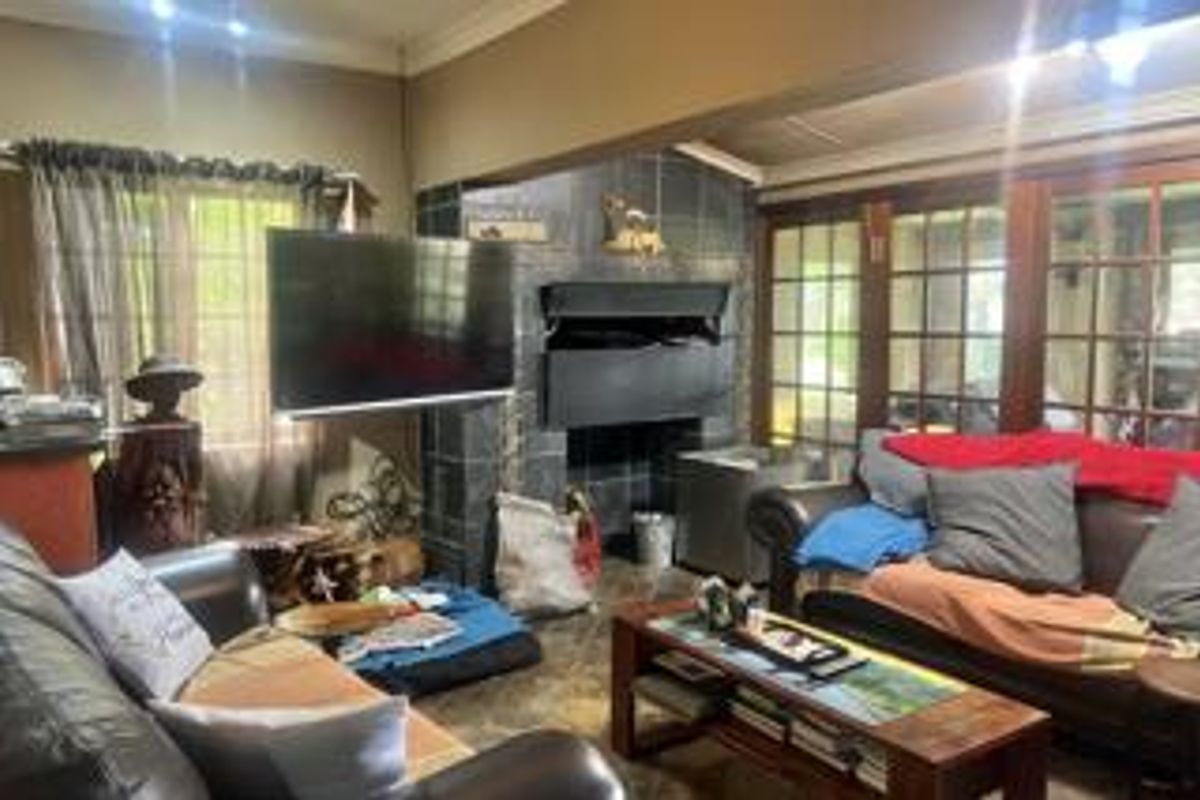 A living room featuring a built-in fireplace with tiled surround and large wooden-framed windows, providing a cozy and traditional atmosphere.