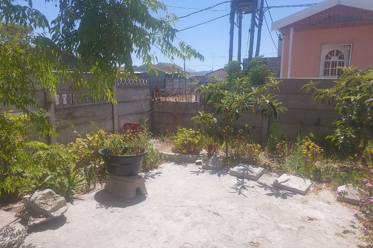 A modest rear garden area featuring a concrete patio slab and precast concrete boundary walls, offering potential for landscaping and outdoor improvement.