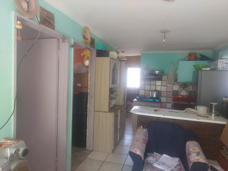 Open plan kitchen and living area featuring tiled flooring, breakfast bar, and dated cabinetry, offering potential for modernization and layout optimization.