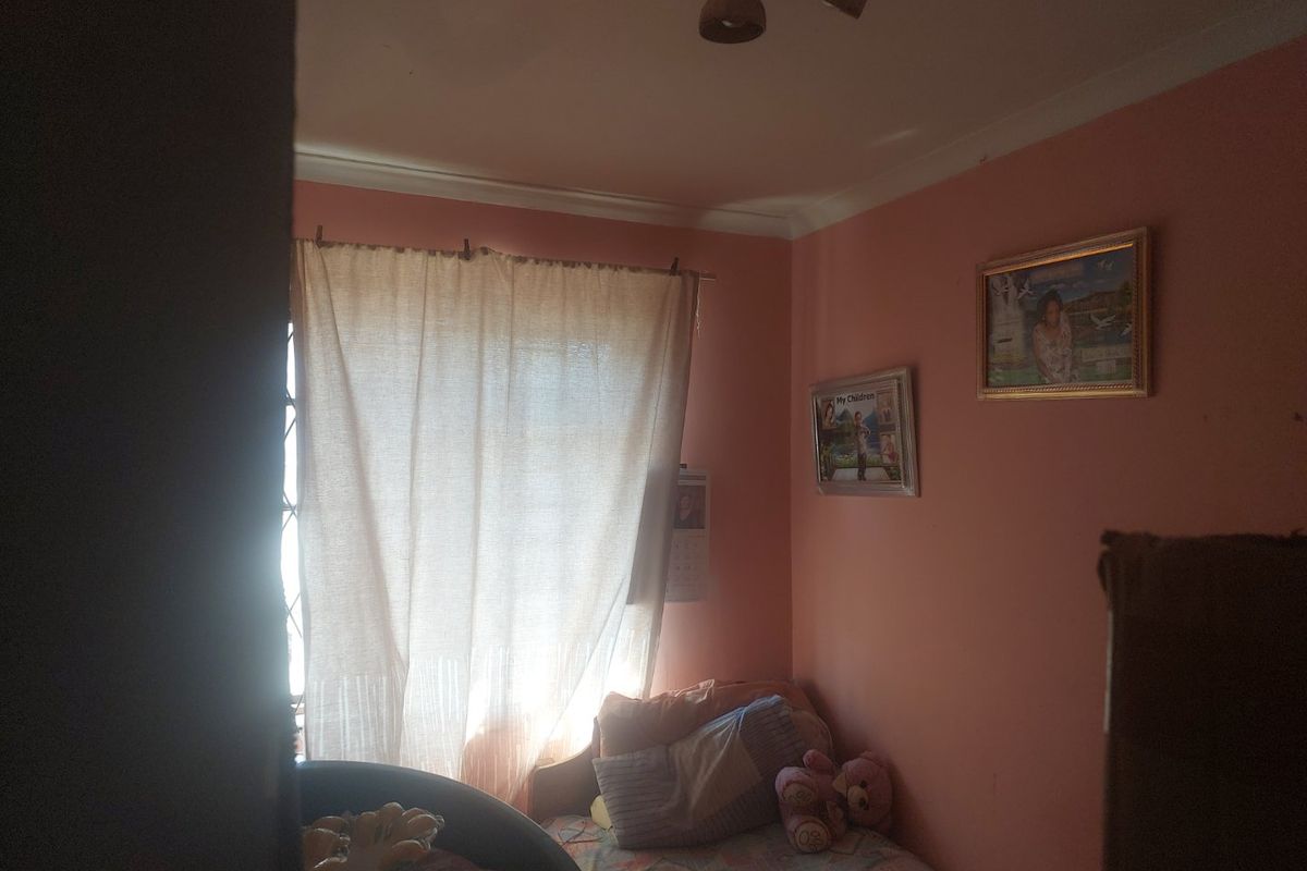 A compact bedroom featuring a window with security gate and ceiling cornice detailing.