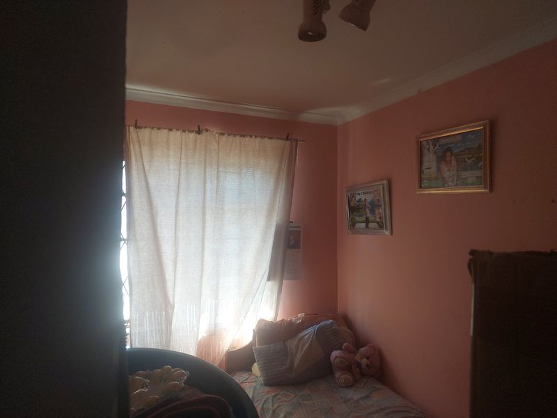 A compact bedroom featuring a window with security gate and ceiling cornice detailing.