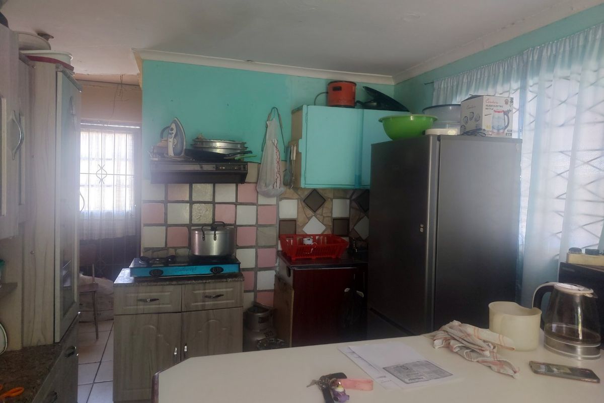 A dated kitchen featuring built-in cabinetry, a gas hob, and a tiled backsplash, offering potential for modernization and cosmetic updates.