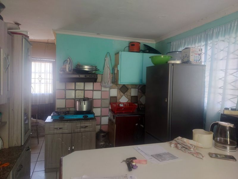 A dated kitchen featuring built-in cabinetry, a gas hob, and a tiled backsplash, offering potential for modernization and cosmetic updates.
