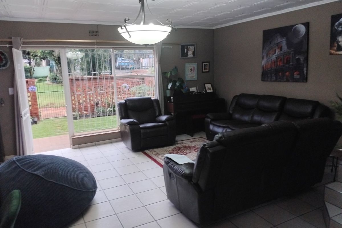 Spacious living room featuring tiled flooring, decorative ceiling tiles, and a large sliding glass door providing direct access to the garden.