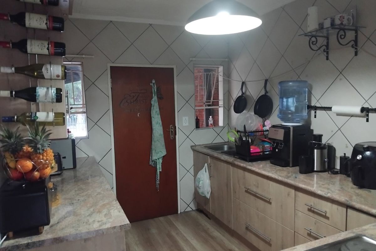 A functional kitchen featuring stone countertops, laminate cabinetry, and a tiled backsplash, providing a practical workspace with integrated storage and lighting.