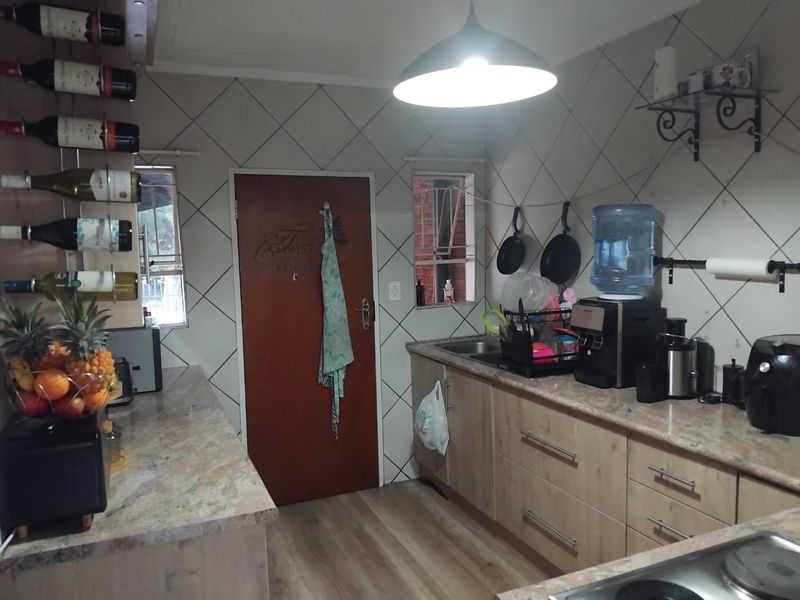 A functional kitchen featuring stone countertops, laminate cabinetry, and a tiled backsplash, providing a practical workspace with integrated storage and lighting.
