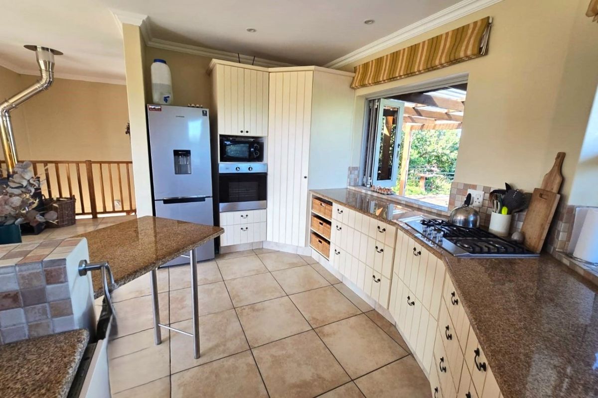 A functional kitchen featuring granite countertops, built-in oven and microwave, gas hob, and ample timber cabinetry with tiled flooring.