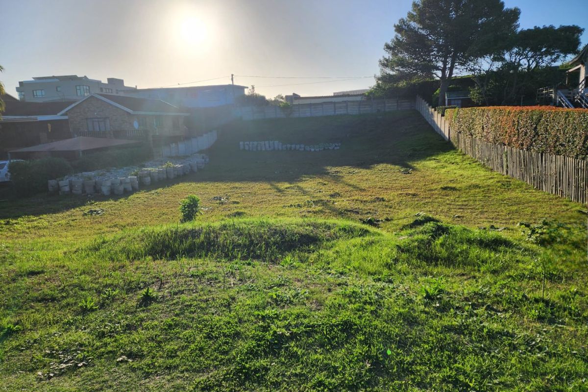 A vacant residential plot featuring a gentle slope, perimeter fencing, and established boundary hedging, offering a clear space for future development.
