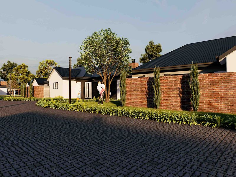 A street-level view of a modern residential development featuring paved roads, brick boundary walls, and contemporary homes with metal roofing.
