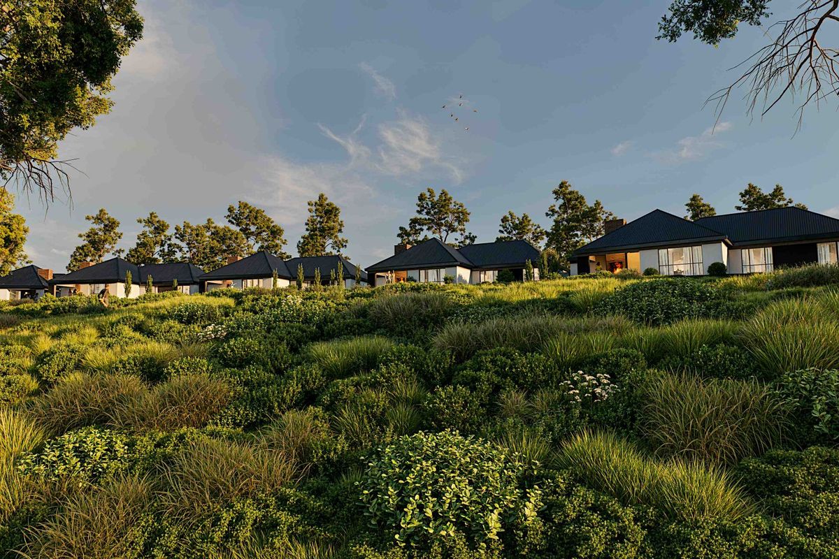 A scenic view of a residential development featuring modern homes with pitched roofs set against a lush, landscaped hillside.