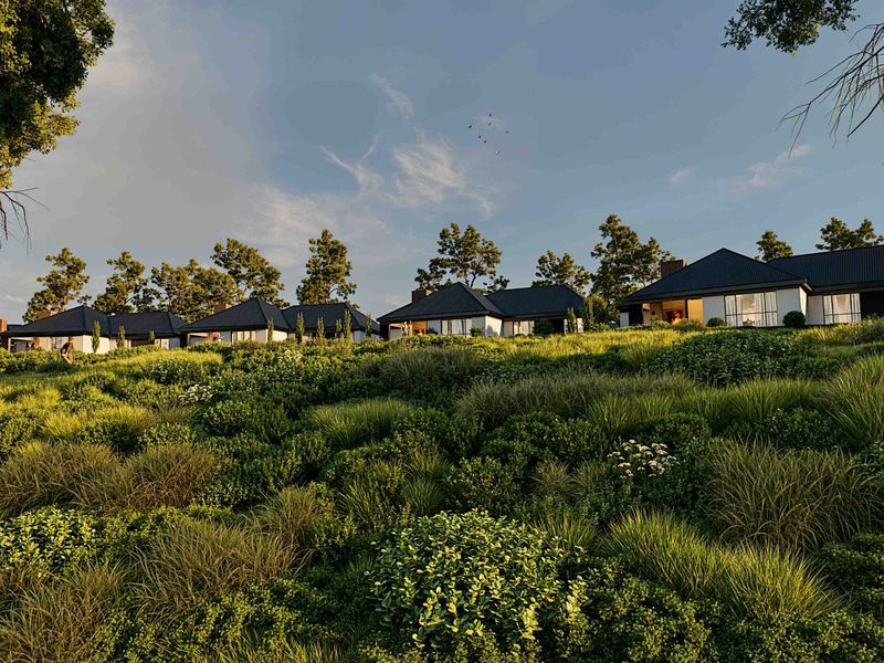 A scenic view of a residential development featuring modern homes with pitched roofs set against a lush, landscaped hillside.