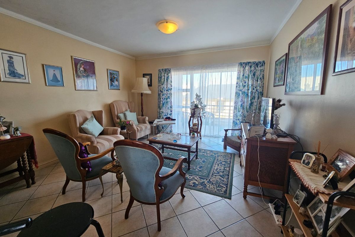 A living room featuring ceramic floor tiles and a large sliding glass door providing access to the balcony.