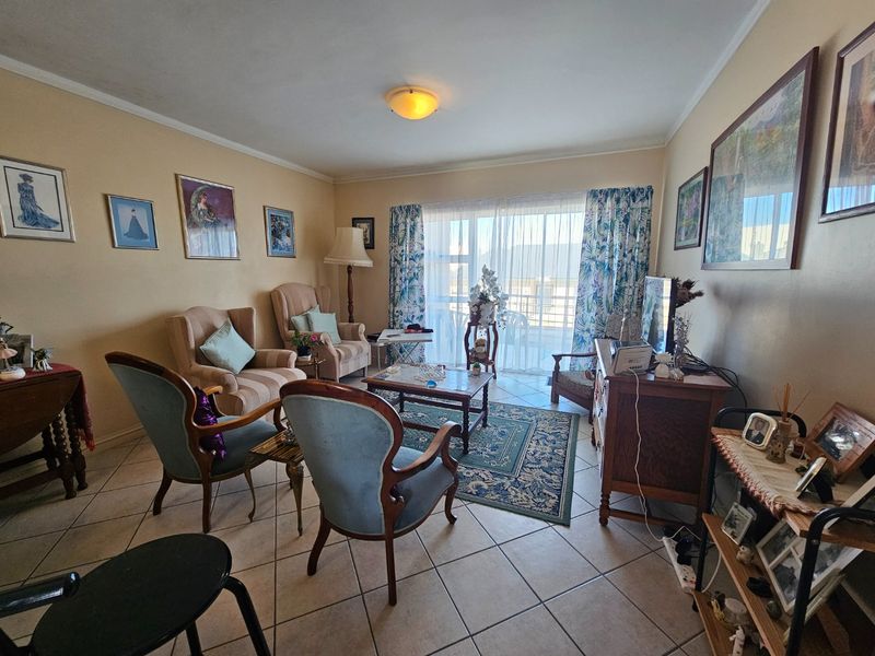 A living room featuring ceramic floor tiles and a large sliding glass door providing access to the balcony.