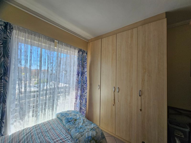 A bedroom featuring light wood-finish built-in cupboards and a sliding door providing access to an outdoor balcony area.