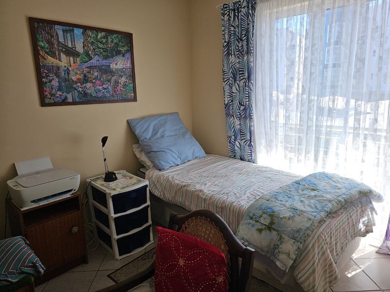 A functional bedroom featuring tiled flooring and a sliding glass door providing natural light and access to an outdoor area.