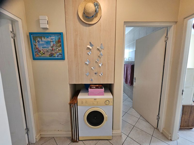 A compact laundry nook featuring built-in cabinetry and tiled flooring, providing functional utility space within the apartment.