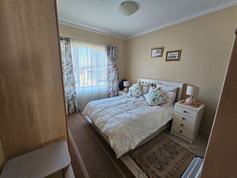 A functional bedroom featuring tiled flooring, a built-in wardrobe, and a window with natural light.