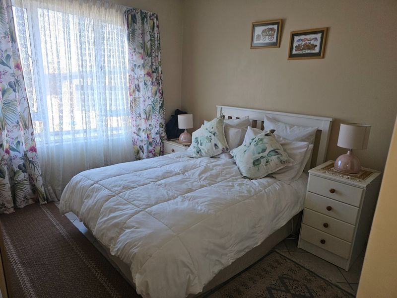 A cozy bedroom featuring tiled flooring and a large window, providing a comfortable and functional sleeping space.
