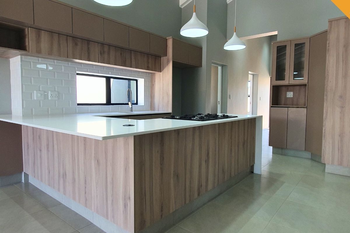 Modern kitchen featuring wood-finish cabinetry, stone countertops, a gas hob, subway tile backsplash, and contemporary pendant lighting in an open-plan layout.