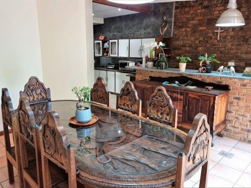 Open plan dining and kitchen area featuring exposed brick walls, tiled flooring, and a breakfast bar with built-in cabinetry.