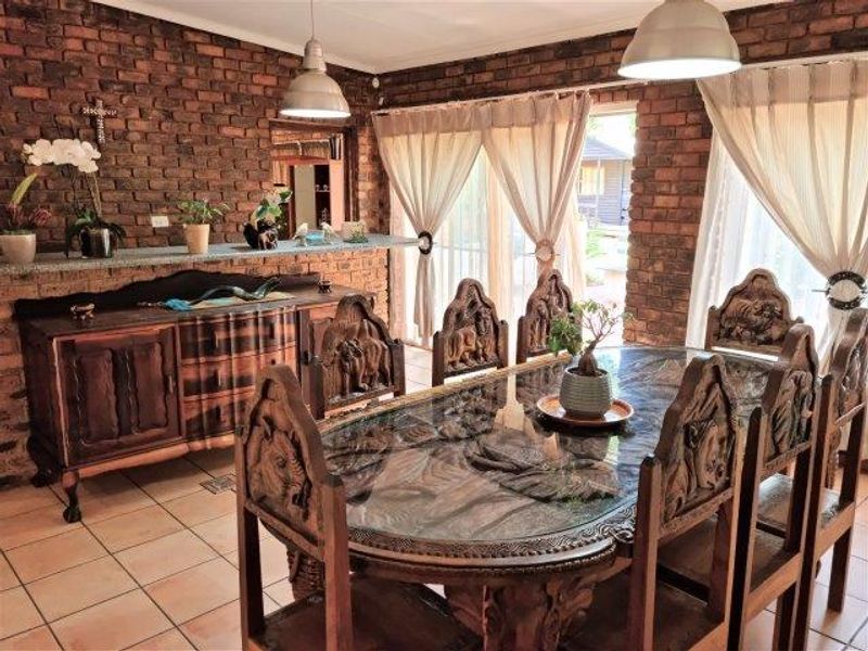 A dining room featuring exposed brick walls, ceramic floor tiles, and large sliding glass doors providing natural light and access to the outdoors.