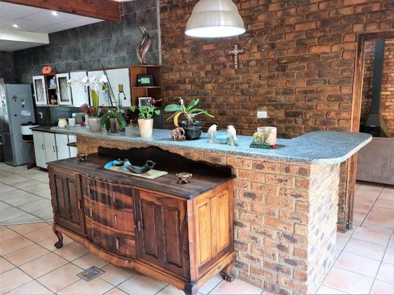 Kitchen area featuring a rustic exposed brick wall, granite-topped breakfast bar, and tiled flooring, offering a warm and characterful space.