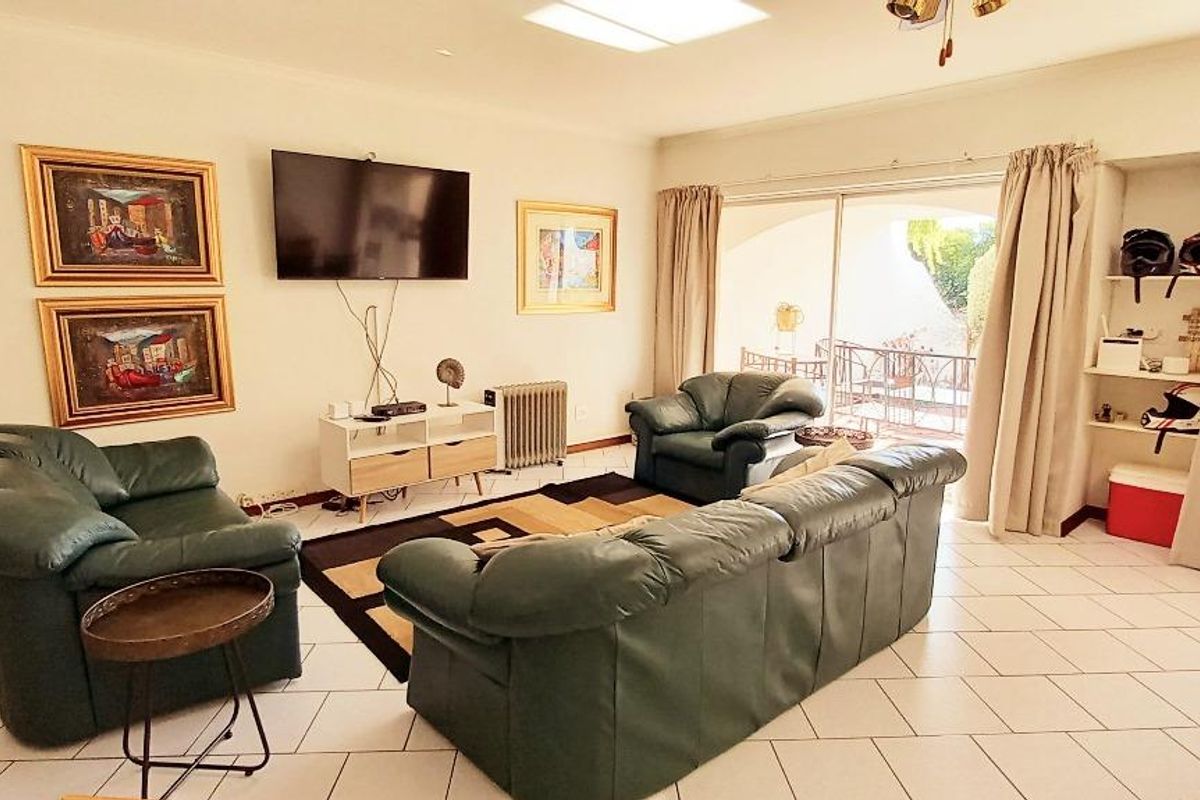 Spacious living room featuring tiled flooring, a skylight for natural illumination, and large sliding glass doors providing access to the outdoor patio area.