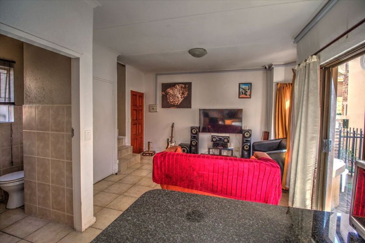 Open plan living area featuring tiled flooring, a granite kitchen counter, and direct access to an outdoor patio through sliding glass doors.