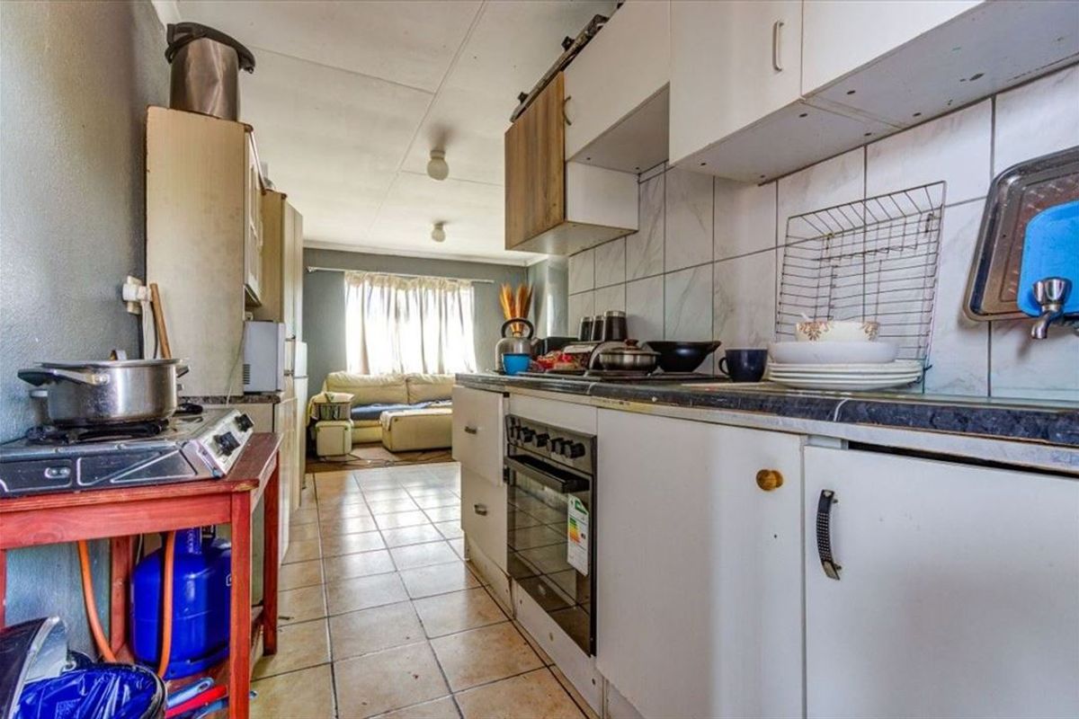 A functional kitchen featuring built-in cabinetry, a tiled backsplash, and an integrated oven, with direct access to the adjacent living area.