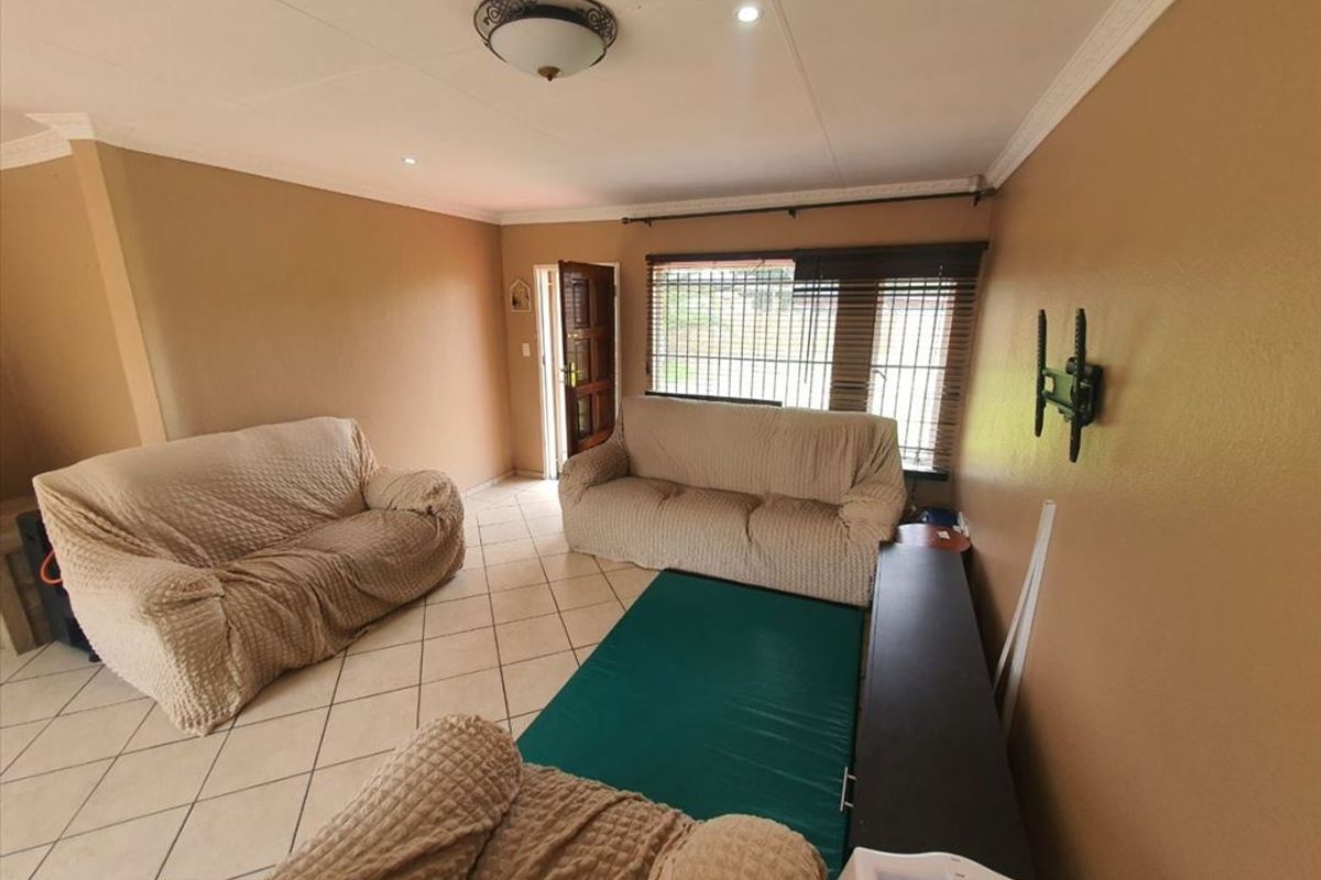 A living room featuring tiled flooring, recessed downlights, and security bars on the windows.