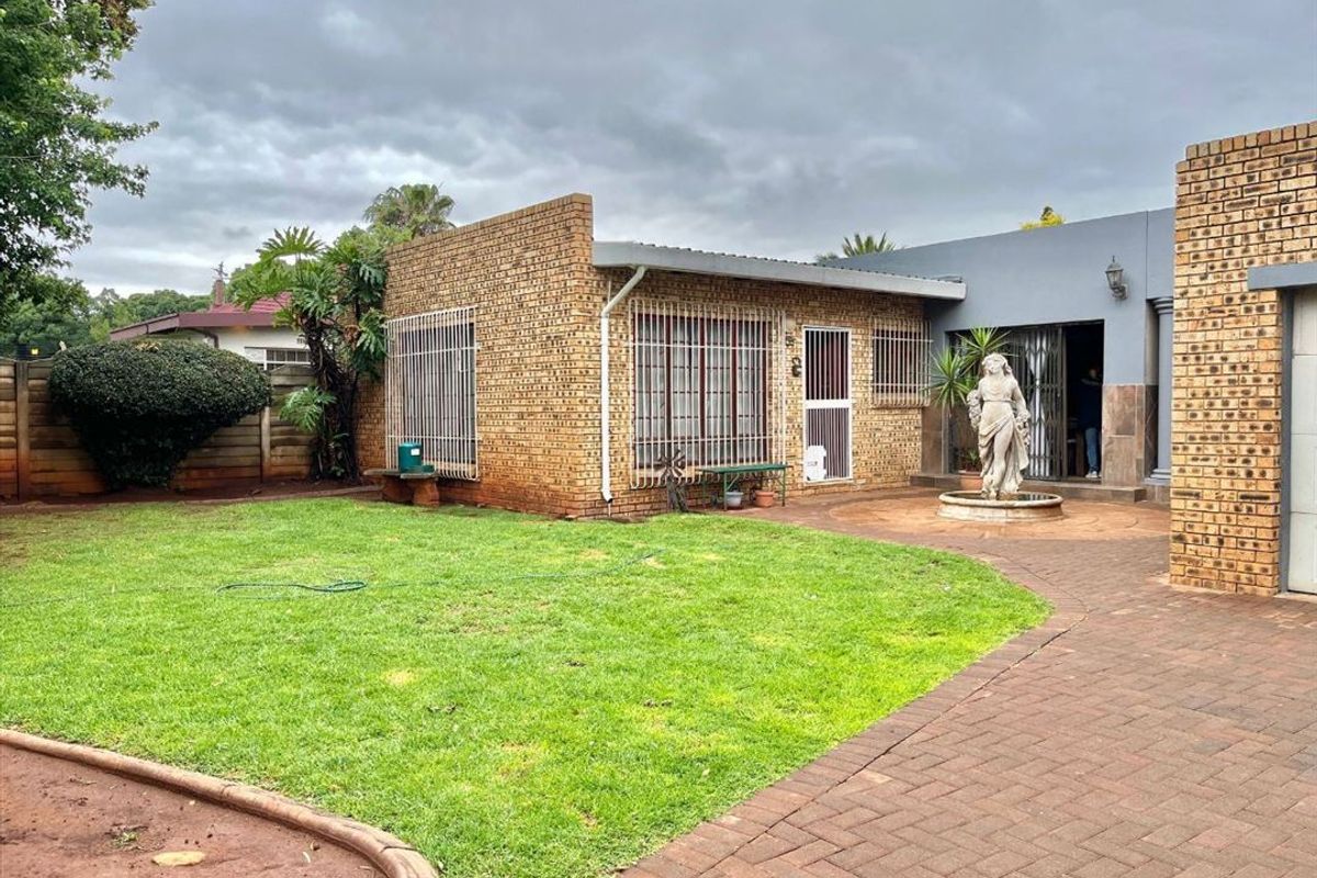 Rear exterior view featuring a face brick facade, paved patio area, and a well-maintained lawn with boundary walling.