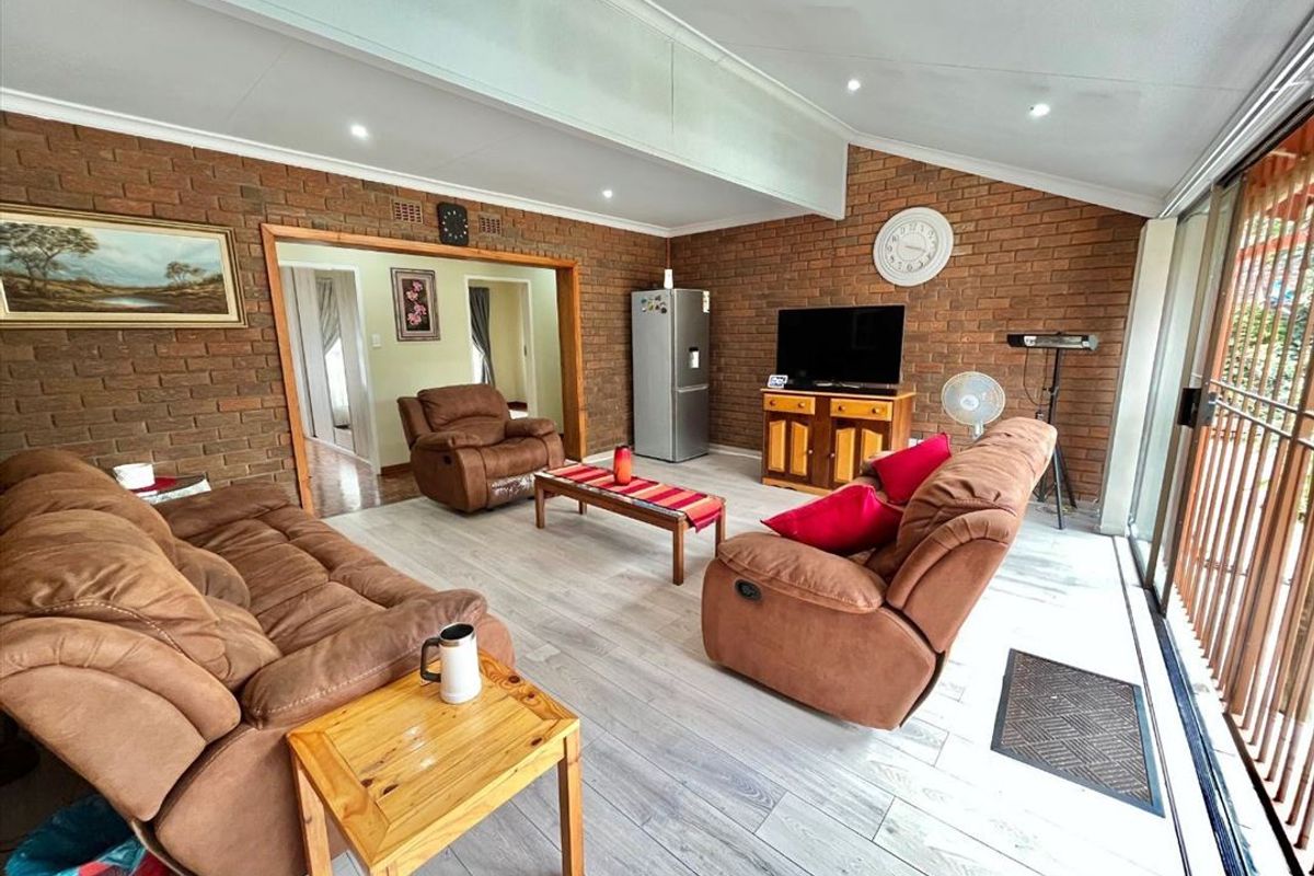 Spacious living room featuring exposed brick walls, recessed downlighting, and large sliding glass doors providing access to the exterior.