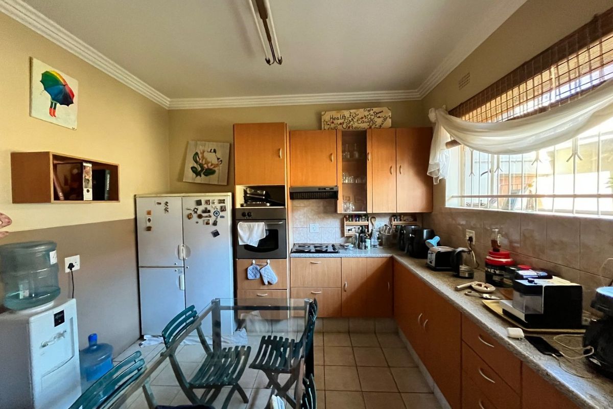 A functional kitchen featuring wooden cabinetry, built-in oven, hob, and tiled flooring, offering a practical layout with potential for modern cosmetic updates.