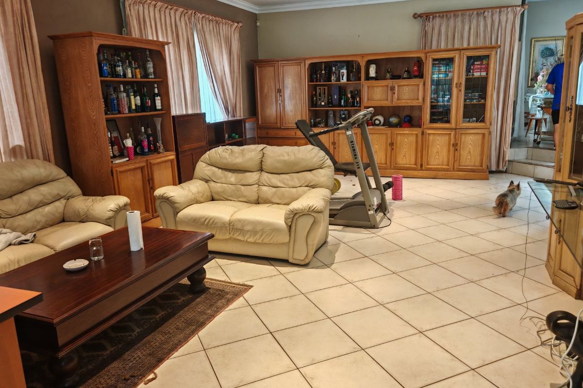 Spacious living area featuring tiled flooring, crown molding, and extensive built-in wooden cabinetry, offering a functional layout with potential for modern updates.