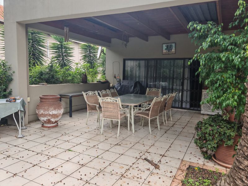 A covered outdoor patio area featuring tiled flooring and exposed timber beams, providing a functional space for outdoor dining and relaxation.