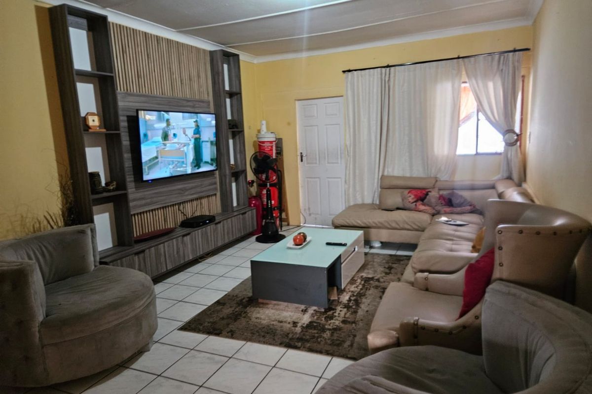 A living room featuring a built-in media wall unit, tiled flooring, and a ceiling fan, providing a functional space for relaxation.