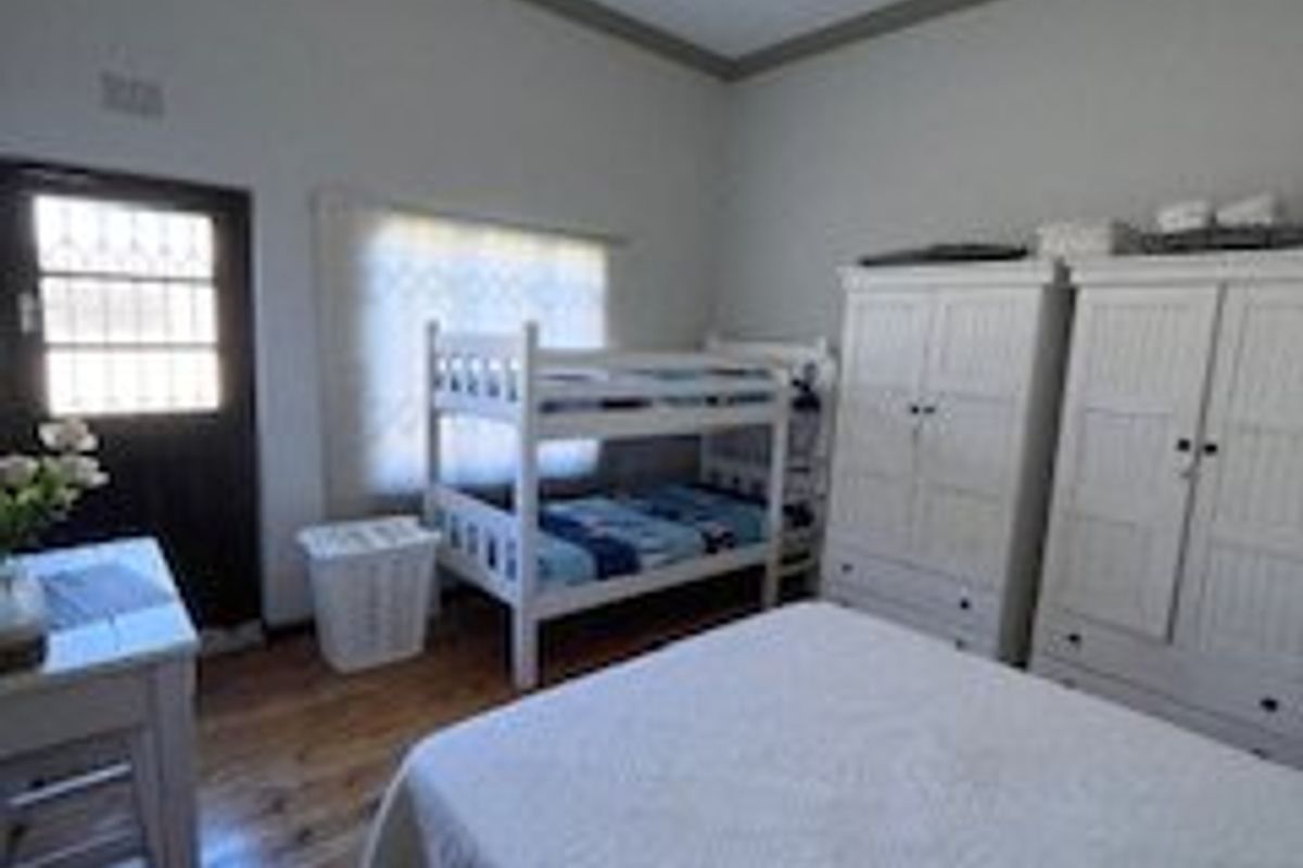 A bedroom featuring hardwood flooring, a security gate, and a ceiling light fixture.