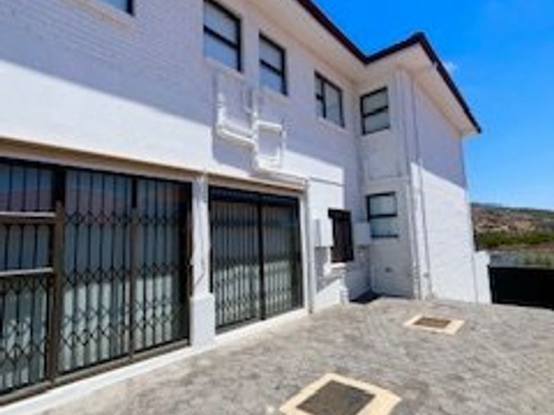 Rear exterior view of the property featuring a paved patio area, white brick facade, and sliding glass doors with security gates.
