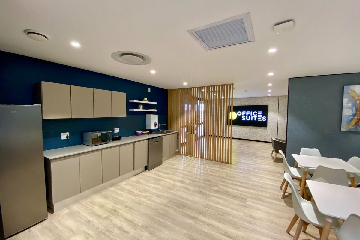 Modern commercial kitchenette featuring sleek built-in cabinetry, laminate flooring, and a decorative timber slat divider, creating a professional and functional breakroom space.