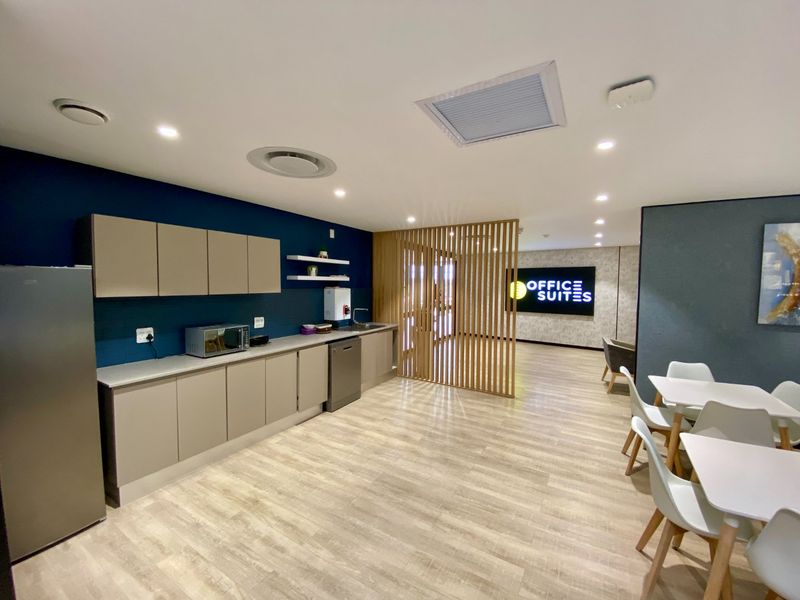 Modern commercial kitchenette featuring sleek built-in cabinetry, laminate flooring, and a decorative timber slat divider, creating a professional and functional breakroom space.