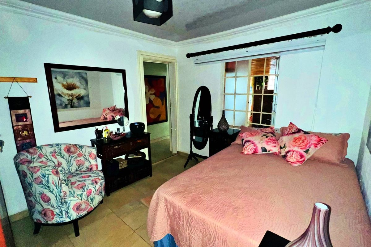 A bedroom featuring tiled flooring, coved ceiling details, and a multi-pane window, providing a functional living space.